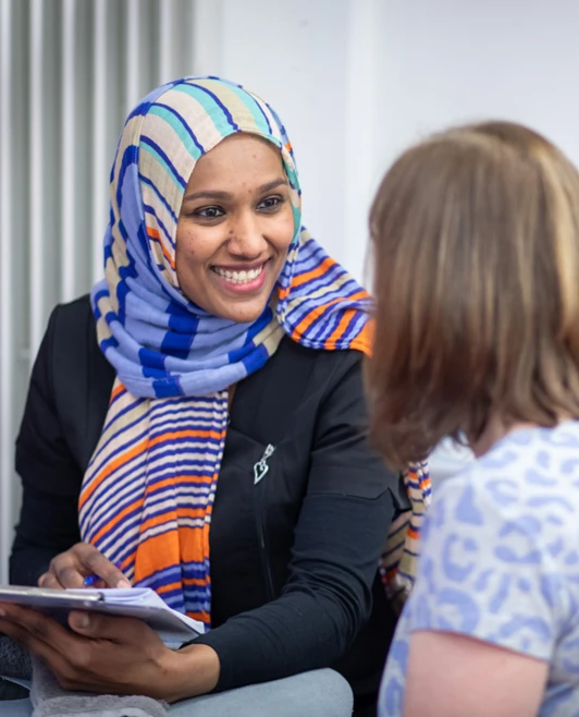 A beauty therapy student consults with a client in a skincare treatment room, wearing a professional uniform and holding a clipboard. A beauty therapy student consults with a client in a skincare treatment room, wearing a professional uniform and holding a clipboard.